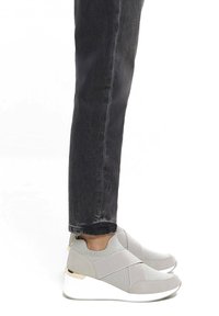 Szare buty sportowe typu slip-on z siateczkowych i zamszowych materiałów, z krzyżującymi się elastycznymi paskami, białą podeszwą na koturnie oraz złotymi akcentami.