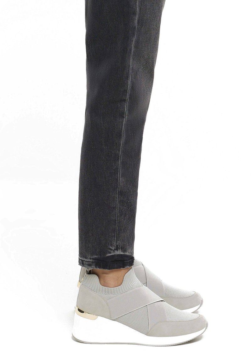 Szare buty sportowe typu slip-on z siateczkowych i zamszowych materiałów, z krzyżującymi si�ę elastycznymi paskami, białą podeszwą na koturnie oraz złotymi akcentami.