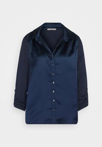 Marineblaue Bluse mit satinierter Vorderseite, kontrastierenden strukturierten Ärmeln, Knopfverschluss und klassischem Kragen. 3/4-Ärmel mit Umschlagoption.