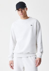 Lys grå sweatshirt i en afslappet pasform, med ribbede manchetter og kant, og et lille sort logo på brystet. Sammen med matchende bukser.