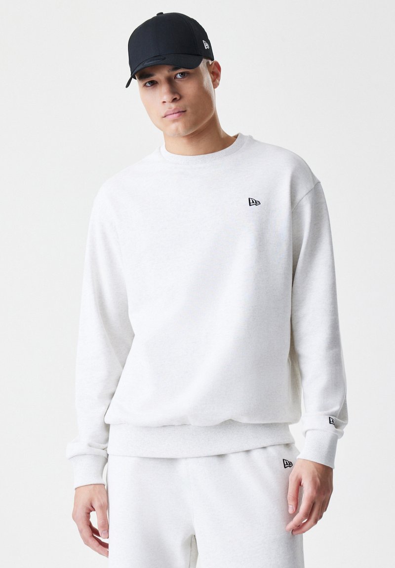 Lys grå sweatshirt i en afslappet pasform, med ribbede manchetter og kant, og et lille sort logo på brystet. Sammen med matchende bukser.