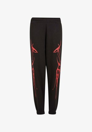 Fekete melegítőnadrág piros absztrakt graffitipattentekkel az oldalán, elasztikus derékpánttal és bokáknál szűkített szegéllyel a testhezálló megjelenés érdekében.