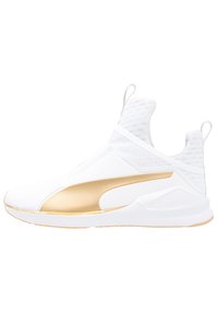 Białe wysokie sneakersy z siateczkowej tkaniny, złotą paskiem po bokach, pętelkami na języku i pięcie, oraz grubą białą podeszwą z jasnobrązowym bieżnikiem.