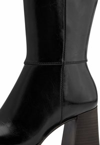 Black leather mid-calf boot with block heel and visible stitching along the shaft and ankle area.