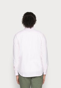 Camicia a maniche lunghe con bottoni di colore rosa chiaro, con sottili strisce bianche. Presenta un colletto classico e un orlo arrotondato. Realizzata in cotone.