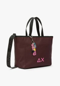 Borsa a tracolla bordeaux con dettagli neri, dotata di manici corti e una tracolla removibile. Include un logo rosa e una decorazione a chiave colorata.