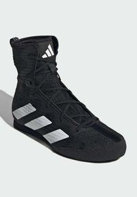 Musta urheilukenkä, jossa on korkea nyöritys, teksturoitu kangas ja selkeä valkoinen kolmiraidallinen merkintä sivulla.