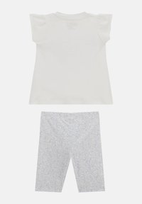 Top bianco a maniche corte con spalline arricciate e leggings leggeri blu chiaro con motivi floreali. Tessuto in cotone, vestibilità casual.