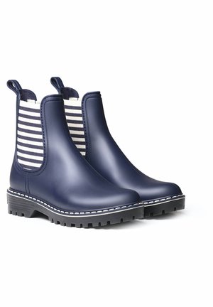 Bottes de cheville imperméables bleu marine avec des panneaux latéraux élastiques rayés, des semelles texturées et des coutures blanches sur les bords.