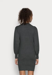 Robe-pull grise avec manches longues bouffantes, poignets et ourlet côtelés. Tissu en maille douce, coupe ajustée, longueur mi-cuisse.