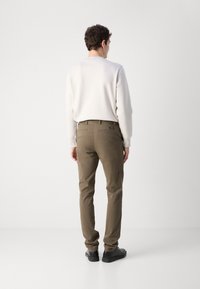Herre khaki chinos med slim fit, blandet bomullsstoff, baklommer og minimale sømdetaljer, kombinert med en lysecolorert genser.