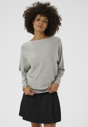 Light gray oversized sweater with a boat neckline and ribbed hem, paired with a black A-line skirt. Smooth texture and relaxed fit.