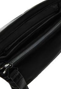 Schwarze Lederhandtasche mit Reißverschluss, verfügt über eine glatte Textur, mehrere Fächer und Beschläge in Silberfarbe. Minimalistisches Design.
