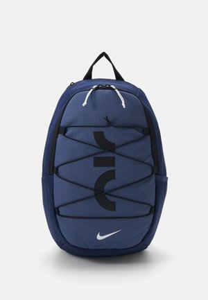 Sac à dos Nike bleu avec des cordons bungee noirs réglables à l'avant, une poignée noire et un logo Nike swoosh blanc en bas.