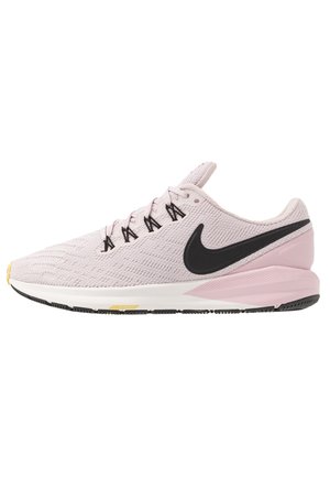 Chaussure de course rose pâle avec le logo Nike noir, lacets noirs, semelle intermédiaire blanche et accents noirs et jaunes sur la semelle extérieure, vue latérale.