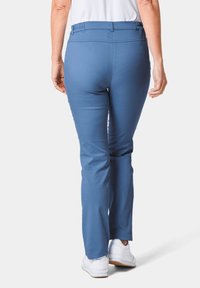 Blauwe broek met een gladde textuur en een recht gesneden ontwerp, voorzien van een elastische tailleband. Draag met witte sneakers op een neutrale achtergrond.