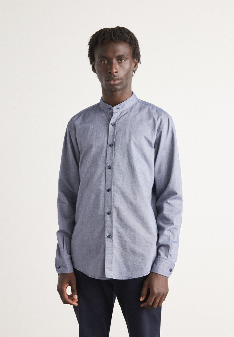 Blauwe chambray shirt met een mandarin kraag, lange mouwen, knoopsluiting aan de voorkant en contrasterende knopen. Gelaagde stof met een casual pasvorm.
