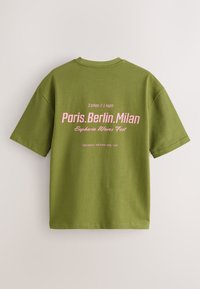 Olijfgroene katoenen T-shirt met korte mouwen. Op de achterkant roze tekst: "Paris.Berlin.Milan" en "Euphoria Waves Fest" met details van de stad en het evenement.