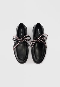 Zwarte leren schoenen met een ronde neus, dikke zool en rood-witte gevlochten veters. Gladde textuur met subtiele stikdetails.