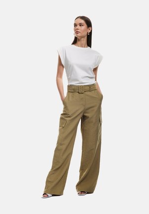 White short-sleeve shirt paired with loose khaki cargo pants featuring a wide waist belt and side pockets. Smooth fabric, relaxed fit.