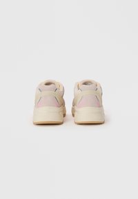 Sneaker mit einem hellbeigen Obermaterial, strukturiertem Stoff, rosa und blauen Akzenten, runder Form und einer Gummisohle mit leichtem Profil.