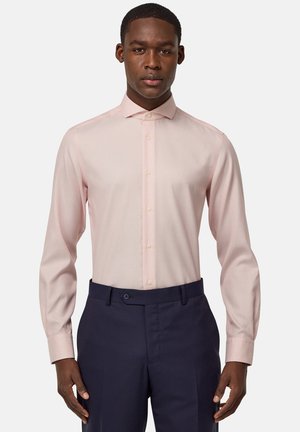 Camicia a maniche lunghe rosa chiaro con vestibilità slim, colletto con bottoni e motivo testurizzato sottile, abbinata a pantaloni tailleur blu scuro.