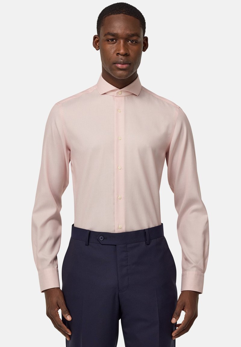 Camicia a maniche lunghe rosa chiaro con vestibilità slim, colletto con bottoni e motivo testurizzato sottile, abbinata a pantaloni tailleur blu scuro.