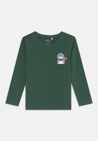 Langärmliges, dunkelgrünes T-Shirt aus weichem Stoff mit einem Cartoon-Tiergrafik auf der linken Brust, die mit einem gestreiften Schal akzentuiert ist.