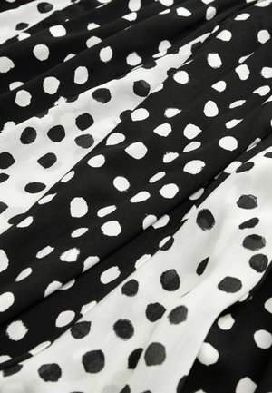 Zwart-wit gestreepte stof met grote, onregelmatige stippen in zwart en wit tegen een gestructureerde achtergrond. Zachte, vloeiende material.