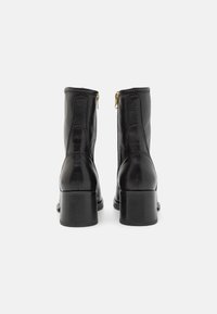 Black leather ankle boots with a smooth finish, side zippers, and a chunky heel for stability. Straight design with minimal stitching details.