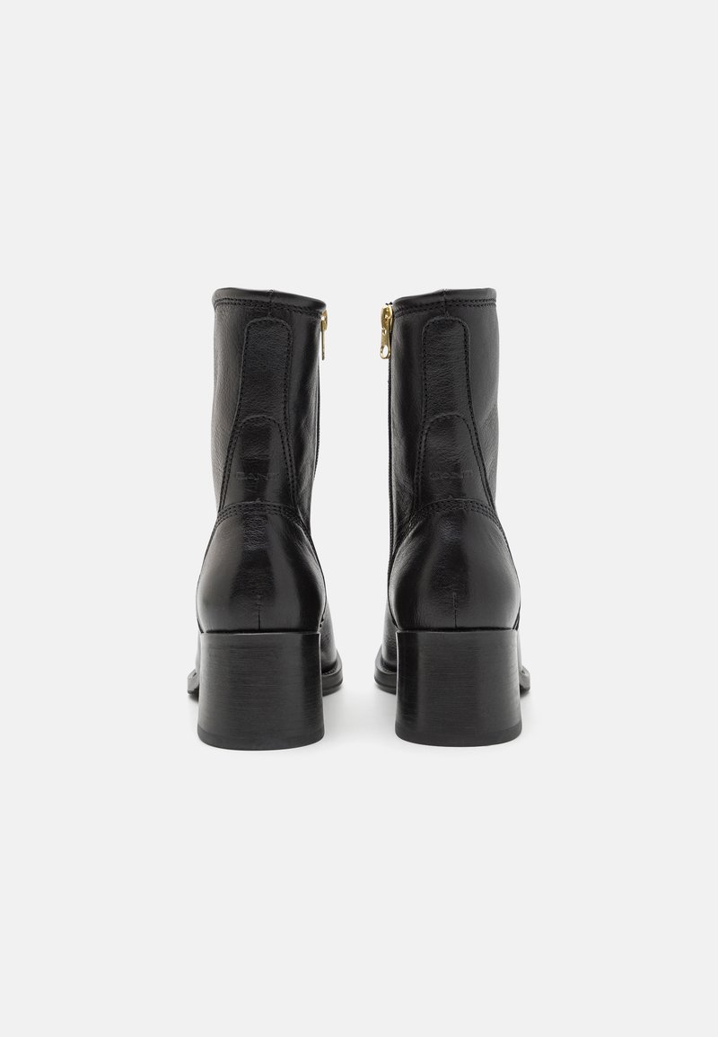 Zwarte leren enkelboots met een gladde afwerking, zijritsen en een chunky hak voor stabiliteit. Recht ontwerp met minimale stiksels.