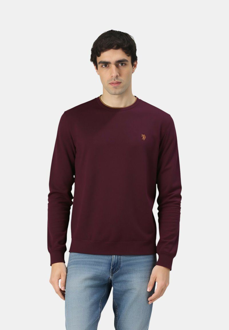 Felpa bordeaux con scollo tondo e maniche lunghe, realizzata in tessuto morbido. Presenta un piccolo logo dorato sul petto a sinistra e polsini a coste.