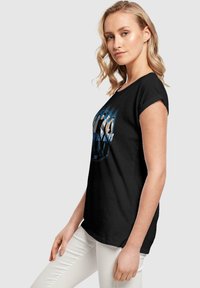 Schwarzes T-Shirt mit rundem Halsausschnitt und kurzen Ärmeln, das einen grafischen Druck von fünf Figuren in Blau- und Weißtönen zeigt.