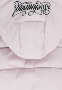 Jasnoróżowa kurtka puchowa z czarnym logo w stylu pisma na przodzie, z pikowanymi sekcjami dla lepszej izolacji i gładkim wykończeniem.