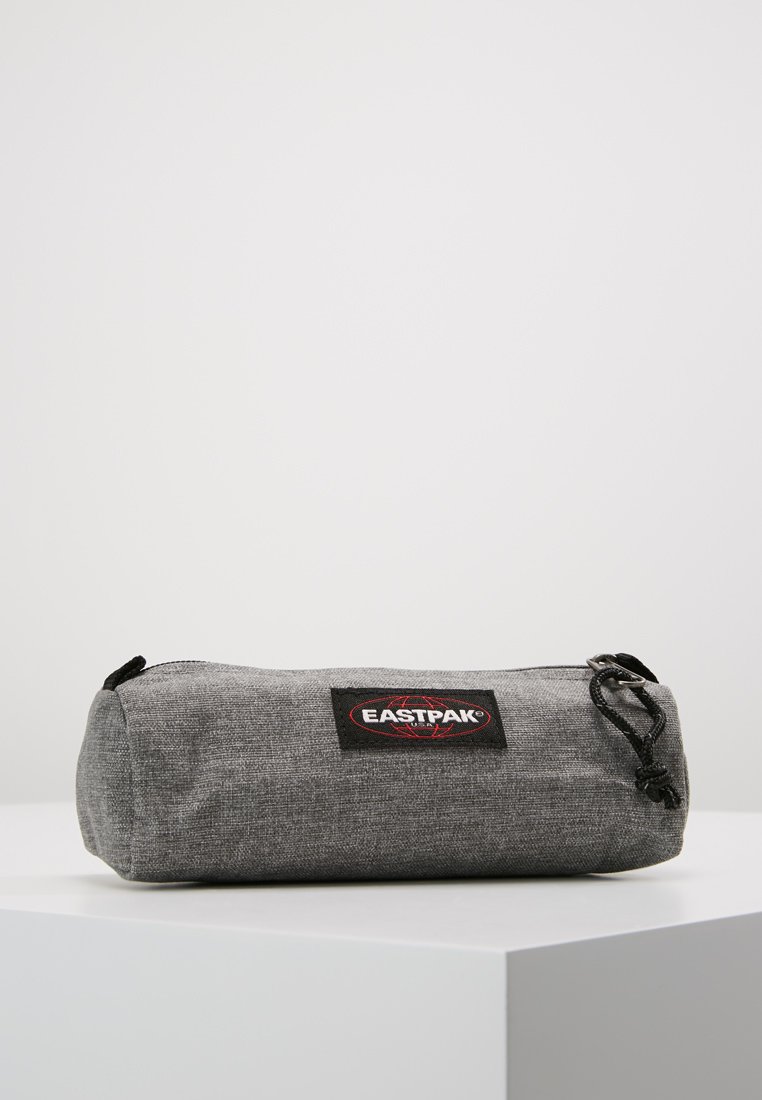 Gray Eastpak pencil case, cylindrical shape, made of textured fabric, features a black logo patch, zip closure, and black drawstring.