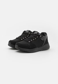 Baskets noires de sport avec une tige en mesh et en daim, bout rond, fermeture à lacets avec des œillets dorés et une semelle en caoutchouc texturé.