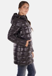 Parka nera imbottita con cappuccio, caratterizzata da una finitura lucida, design a righe orizzontali, tasche laterali e dettagli in zip color oro.