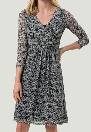 Schwarz-wei dresses mit einem Blattmuster, V-Ausschnitt, dreiviertel durchsichtigen Ärmeln, taillierter Taille und fließendem Rock.