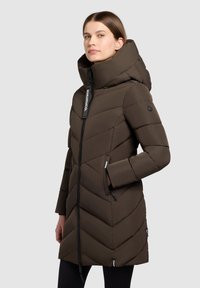 Cappotto imbottito marrone con cappuccio, caratterizzato da un design a rombi trapuntato, chiusura con zip e tasche laterali. Accenti neri con dettaglio logo sulla zip.