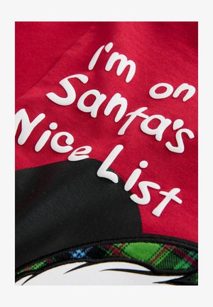 Raudona medžiaga su balta pakeltu tekstu, kuris skaito "Aš esu ant Švento Kalėdų Senelio gerųjų sąrašo," su juodu ir languotu akcentu apačioje.