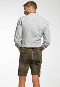 Herrenhemd in Grau mit Karomuster und langen Ärmeln, kombiniert mit braunen Leder-Shorts, die seitliche Taschen und eine strukturierte Oberfläche aufweisen.