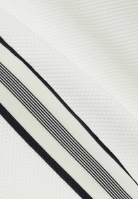 Material texturat de culoare albă, cu dungi diagonale negre și un accent îngust de culoare neagră, punând în evidență un design stratificat și o suprafață tactilă.