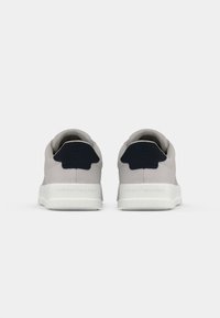 Pair of light gray sneakers with dark blue heel tabs and white soles, viewed from the back on a plain white background.