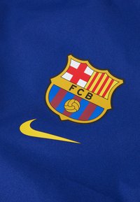 Tissu bleu présentant le logo du FC Barcelone avec un design de rayures rouges et jaunes. Comprend un swoosh jaune de Nike sous le logo.