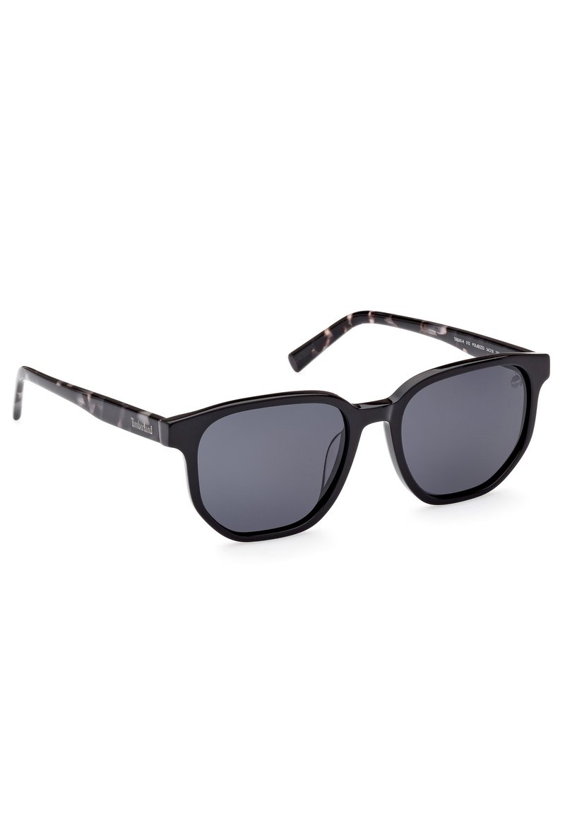 Gafas de sol negras rectangulares con lentes oscuros. Montura de acetato con acabado brillante y brazos de las patillas estampados en negro y gris.