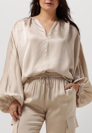 Beige satin blouse with a V-neckline, gathered shoulders, and balloon sleeves. Paired with matching lightweight elastic waist pants.