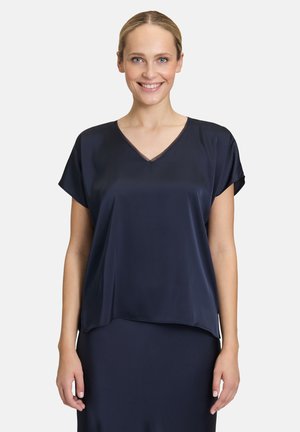 Blusa di seta blu navy con scollo a V, maniche corte e una vestibilità fluida. Presenta una texture liscia e un leggero lucido.