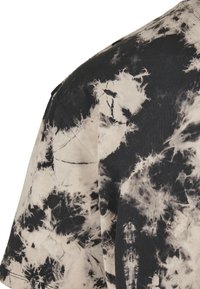Korteermet t-skjorte med tie-dye mønster i svart og beige, laget av bomull med en myk tekstur og en avslappet passform.