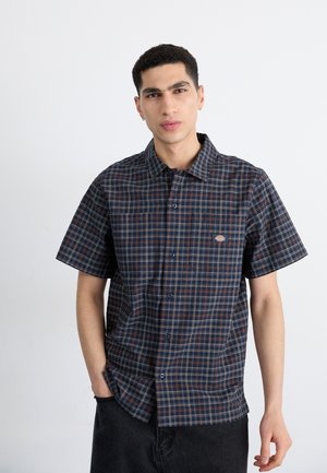 Camicia a maniche corte, a quadri blu navy con taschino, dotata di design con bottoni e motivo a griglia rosso e bianco in contrasto. Tessuto di cotone.