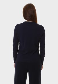 Maglione lavorato a maglia di colore blu navy, a maniche lunghe e con scollatura tondeggiante. Tessuto morbido, vestibilità aderente e dettagli a coste sui polsini e sull'orlo.